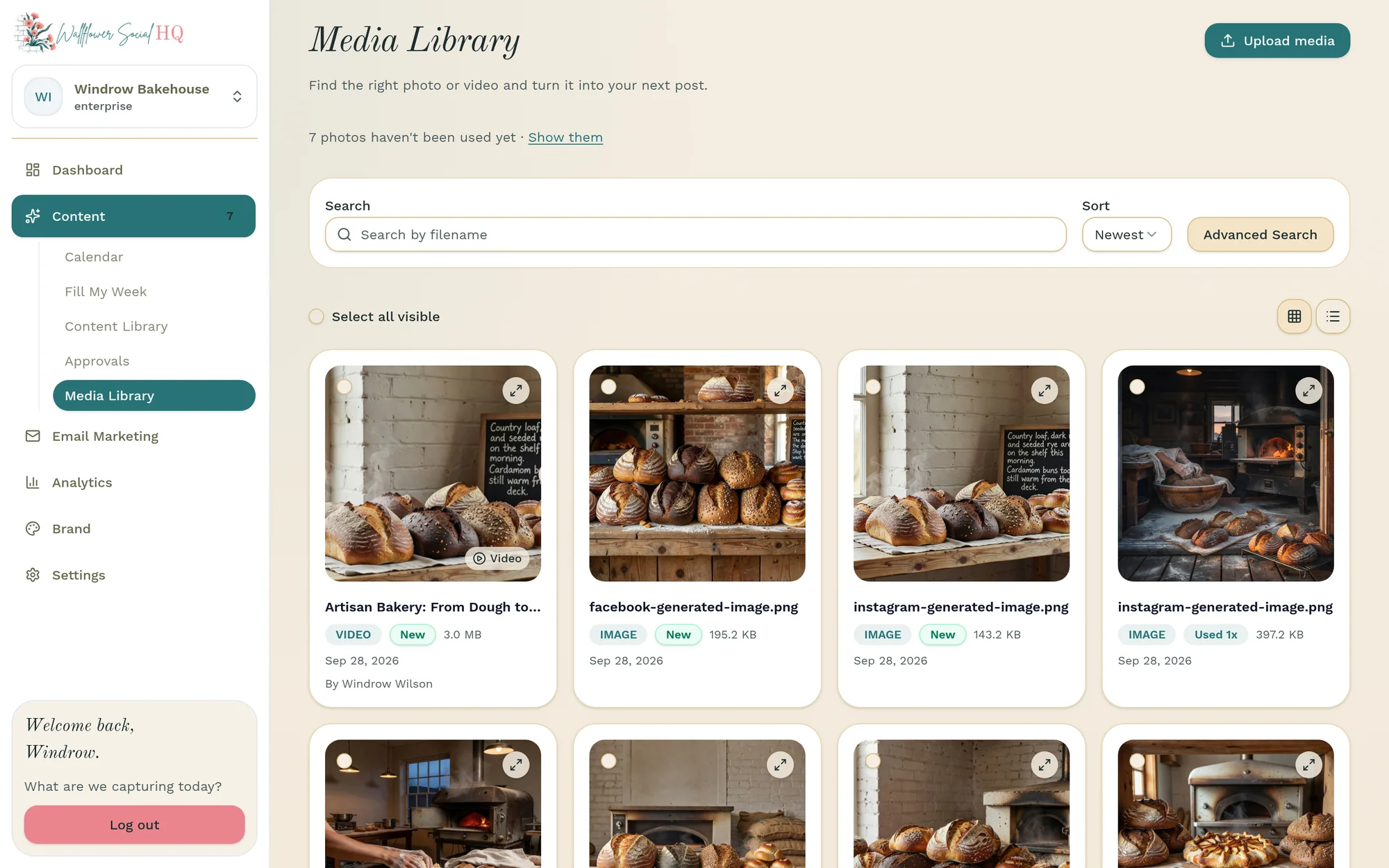 The Media Library for Windrow Bakehouse, noting that 7 photos haven't been used yet, with search and sort above a grid of bakery photos and a video. The newest is a video, “Artisan Bakery: From Dough to…”, marked New and added by Windrow Wilson on Sep 28, 2026, next to loaves on wooden shelves and by the bread oven.